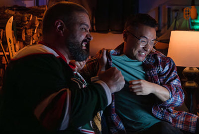 Two men cheering while they watch a hockey game on TV.