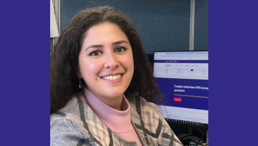 Joelle smiling at her desk with the Eastlink website visible on her desktop computer.