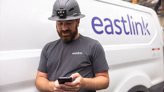 A technician standing in front of a white Eastlink work van.