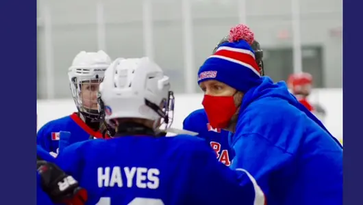 Gerry Hayes at the rink coaching three young hockey players.