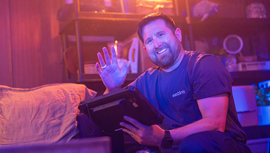 An Eastlink technician smiling and waving while he installs a customer's internet service.
